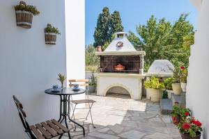 a patio with a fireplace and a table and chairs at Casa Mia Skopelos - Spacious 3-Bedroom House near Stafylos Beach in Skopelos Town