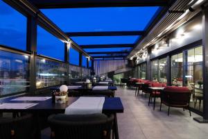 a restaurant with tables and chairs and windows at The Alpfine Hotel in Ankara