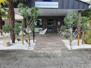a front entrance to a building with chairs and trees at Hotel Ibis Budget Deauville in Deauville