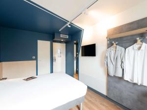 a bedroom with a white bed and a blue wall at ibis budget Lyon Centre Confluence in Lyon