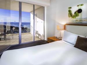 a bedroom with a large bed and a balcony at The Sebel Maroochydore in Maroochydore