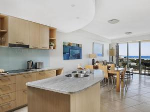 a kitchen with a sink and a table with chairs at The Sebel Maroochydore in Maroochydore