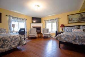 a bedroom with two beds and chairs and a fireplace at Butterfly Manor in Niagara Falls