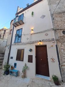 a white building with a brown door on a street at Gredò Home & SPA in Gratteri