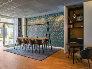 a dining room with a table and chairs against a wall at Aparthotel Adagio Access La Défense Puteaux in Puteaux