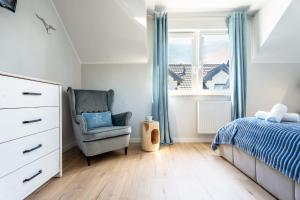 a bedroom with a bed and a chair and a window at Apartamenty Lagos in Karwia +60 photos