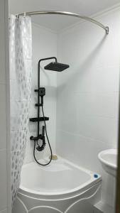 a white bathroom with a shower curtain and a sink at Apartments Aibergenova 4 in Shymkent