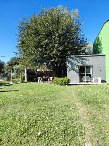 a house with a tree next to a yard at Las catalinas in General Rodríguez