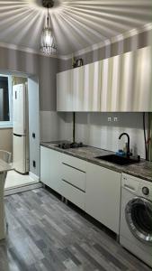 a kitchen with white cabinets and a refrigerator at Apartments Aibergenova 4 in Shymkent