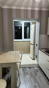 a kitchen with a table and a refrigerator at Apartments Aibergenova 4 in Shymkent