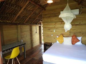 a bedroom with a bed and a desk and a chandelier at Ecopayara Hotel Puerto Gaitán in Puerto Gaitán