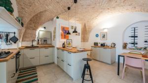 a kitchen with white cabinets and a brick wall at Casa Superga by Rentbeat in Cisternino