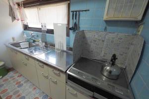 a kitchen with a stove with a tea kettle on it at ライダーハウスみかさんち in Marugame