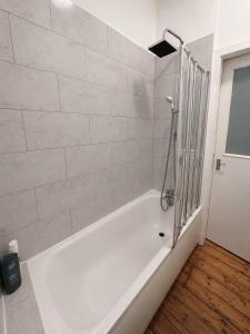 a white bath tub with a shower in a bathroom at Comfortable 2 Bedroom Flat in Leith in Edinburgh