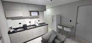 a kitchen with white cabinets and a couch in a room at RG Kitnet02 in Curitiba