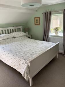 a white bed in a bedroom with a window at Brook Lodge, One bed house in AONB Dorset with swimming pool in Iwerne Minster
