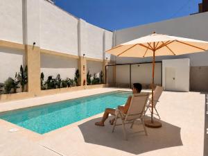 a man sitting in a chair next to a pool with an umbrella at Maritime Coliving Valencia in Valencia +63 photos