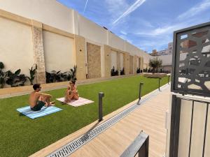 two people sitting on the grass outside of a building at Maritime Coliving Valencia in Valencia