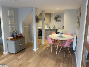 a kitchen and dining room with a table and pink chairs at Brook Lodge, One bed house in AONB Dorset with swimming pool in Iwerne Minster