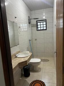 a bathroom with a toilet and a sink and a mirror at Apto aconchegante 02 in Aquidauana +1 photo