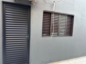 a gray building with a window and a shutter at Apto aconchegante 02 in Aquidauana