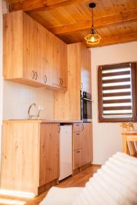 a kitchen with wooden cabinets and a white refrigerator at Vikendica Vinogradski Mir, Jacuzzi and Vineyard View in Bačinci