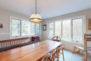 a dining room with a wooden table and some windows at Walk to the Lakes in Ludlow