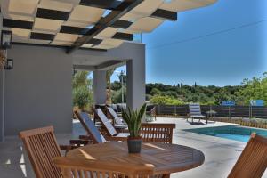 a patio with a wooden table and chairs and a pool at Villa GEIA in Klísmata