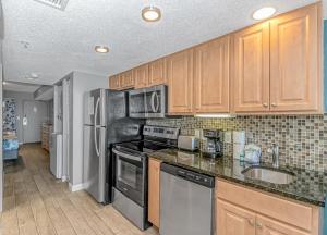 a kitchen with wooden cabinets and stainless steel appliances at Atlantica 1055 in Myrtle Beach +32 photos