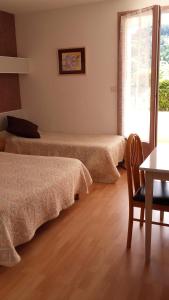 um quarto com duas camas, uma mesa e uma cadeira em Hotel Saint Jacques em Vals-les-Bains