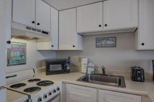a kitchen with white cabinets and a sink and a stove at The Palace 505 in Myrtle Beach +27 photos