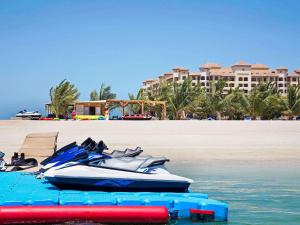 a speed boat on the beach next to a beach at Pullman Resort Al Marjan Island in Ras al Khaimah