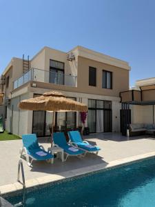 a couple of chairs and an umbrella and a swimming pool at Royal Pearl Villa 1 in Sowayma