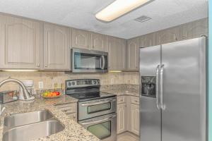 a kitchen with wooden cabinets and a stainless steel refrigerator at Atlantica 757 in Myrtle Beach +45 photos