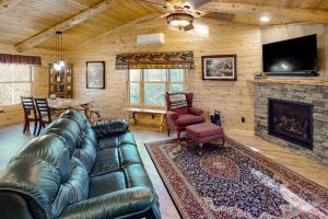 a living room with a leather couch and a fireplace at Blackbear Log Cabin in Morrisville