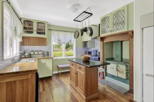 a kitchen with green cabinets and a black counter top at Sanctuary Cottage in Karapiro