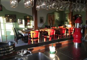 a restaurant with a bar with red chairs and a mirror at Hotel Zur Buche in Bockhorn