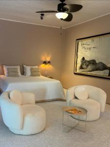 a bedroom with a bed and two chairs and a table at Pousada Jardim Boêmio in Cananéia