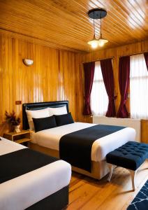 two beds in a room with wooden walls and windows at Deal Otel in Uzungöl