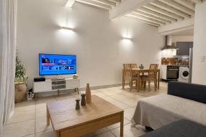 a living room with a couch and a tv at Bright Nîmes Center Flat with Terrace in Nîmes