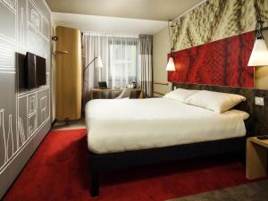 a hotel room with a large bed with a red carpet at ibis Cambridge Central Station in Cambridge