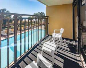 a balcony with two chairs and a swimming pool at Relaxing Oceanfront Condo - Holiday Pavilion 211 in Myrtle Beach