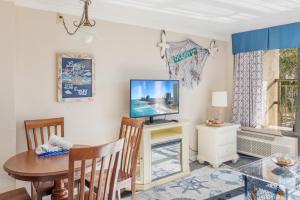 a dining room with a table and a tv at Relaxing Oceanfront Condo - Holiday Pavilion 211 in Myrtle Beach +32 photos