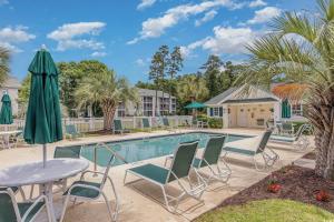 a swimming pool with chairs and a table and umbrella at Charming Golf Getaway! River Oaks 19E in Myrtle Beach