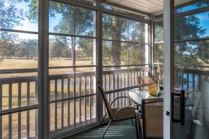 a screened porch with a table and chairs and windows at Charming Golf Getaway! River Oaks 19E in Myrtle Beach