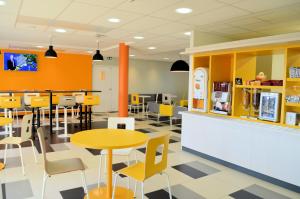 a restaurant with yellow chairs and tables and a counter at Premiere Classe Le Havre Centre-LES DOCKS in Le Havre