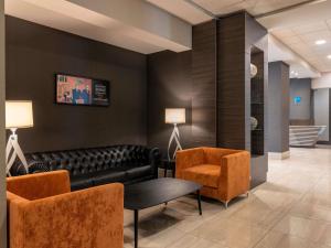 a waiting room with a black leather couch and chairs at Novotel Brescia Due in Brescia
