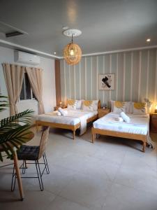 a room with two beds and a table and a chair at Bellas Guest House in Pooc