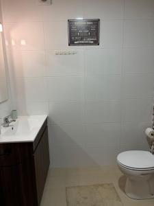a white bathroom with a toilet and a sink at Kasa102 in Gouveia +2 photos