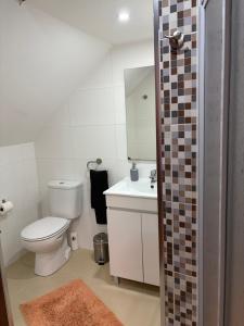a white bathroom with a toilet and a sink at Kasa102 in Gouveia